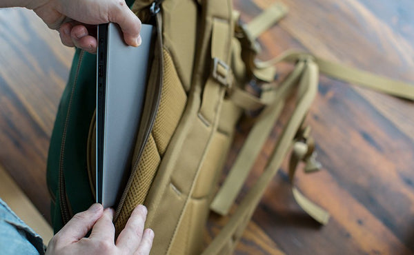 A person putting a laptop into the laptop compartment of the Guide's Edition Synik 22.